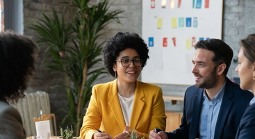 Drei Frauen und ein Mann sitzen in einem Meeting